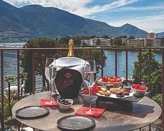 Spazio esterno con sedie e tavoli, vista su giardino e lago.